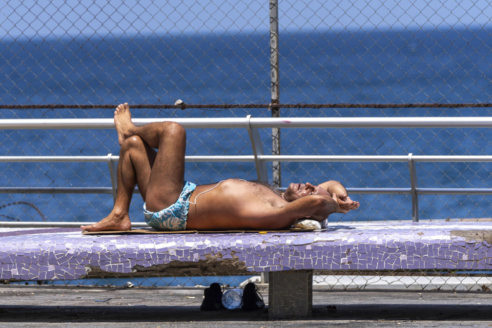 A man sunbathes at Beirut's seaside promenade, along the Mediterranean Sea, on a sweltering hot day, in Beirut, Lebanon, Friday, July 26, 2024. (AP Photo/Hassan Ammar)