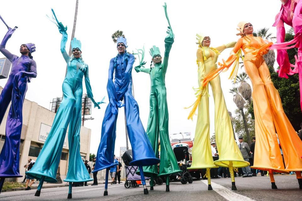 A group of stilt walkers in different colors of the rainbow participate in the Los Angeles Pride Parade.