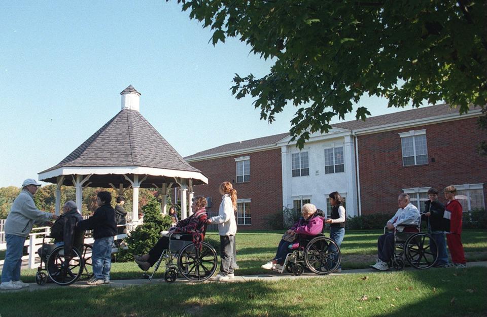 Students from Roosevelt Elementary School and seniors line up on a concrete walkway as they go out to the courtyard at Applewood Estates in Freehold Township to plant flower bulbs in this 1999 file photo.