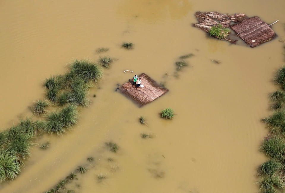 <p>People affected by flooding stand on a partially submerged house as they wait to receive food parcels being distributed by a Indian Air Force helicopter on the outskirts of Allahabad, India, August 25, 2016. (REUTERS/Jitendra Prakash)</p>