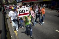 A woman holds up a sing that in Spanish read "No more dictatorship" as they walk along to gather for a demonstration against President Nicolas Maduro in Caracas, Venezuela, Saturday, April 8, 2017. Opponents of President Nicolas Maduro are preparing to flood the streets of Caracas on Saturday as part of a week-long protest movement that shows little sign of losing steam. (AP Photo/Ariana Cubillos)