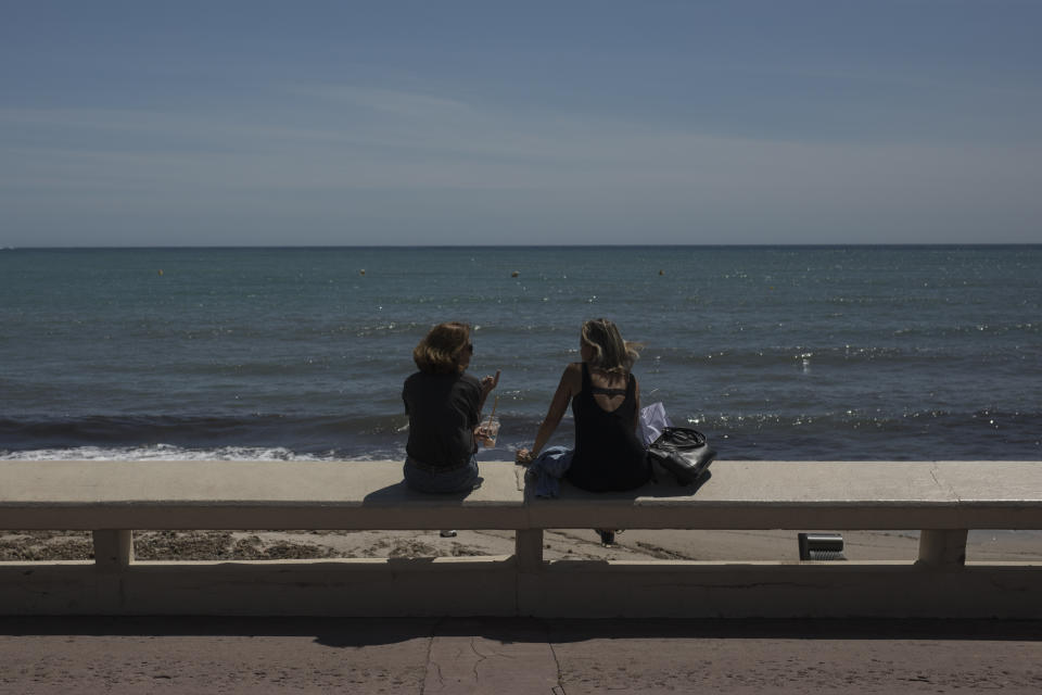 Two women sit above the deserted Croisette beach due to measures put in place to stop the spread of the coronavirus in Cannes, southern France, Tuesday, May 12, 2020. The Cannes Film Festival won't kick off as planned on Tuesday. The festival's 73rd edition has been postponed indefinitely, part of the worldwide shutdowns meant to stop the spread of the coronavirus. (AP Photo/Daniel Cole)