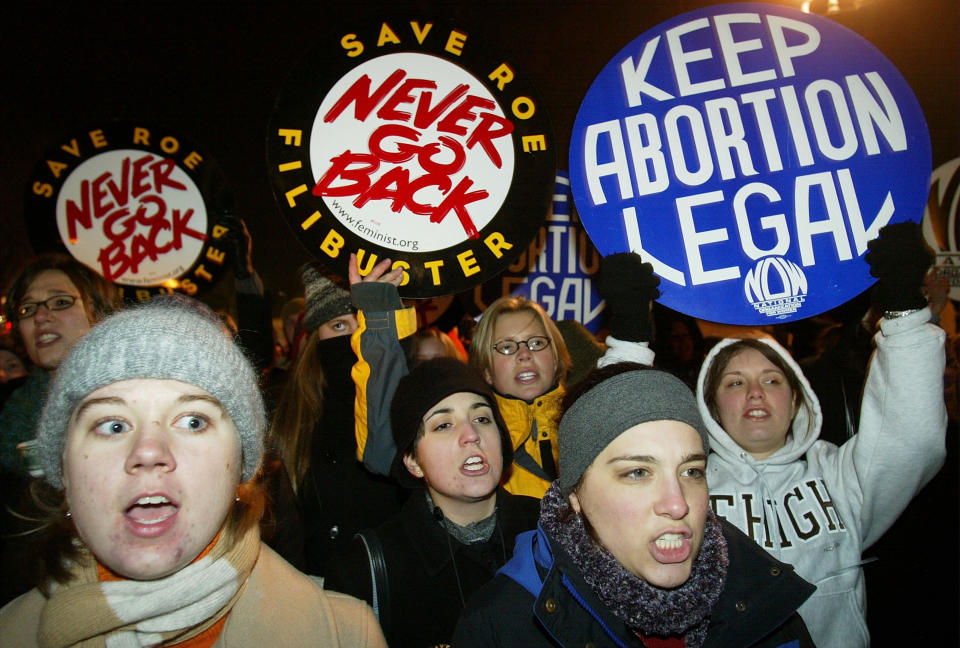 Demonstrators hold up signs reading "never go back" and "keep abortion legal"