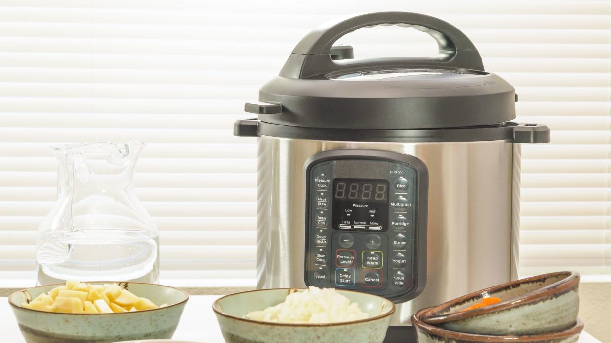 Modern electric multi cooker with some ingredients for cooking needs close up on kitchen table