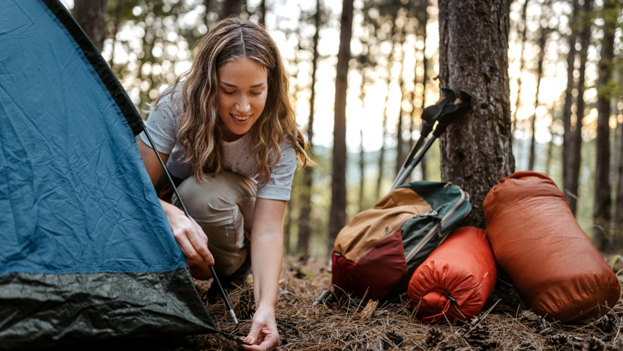  Woman pitching tent in woods 