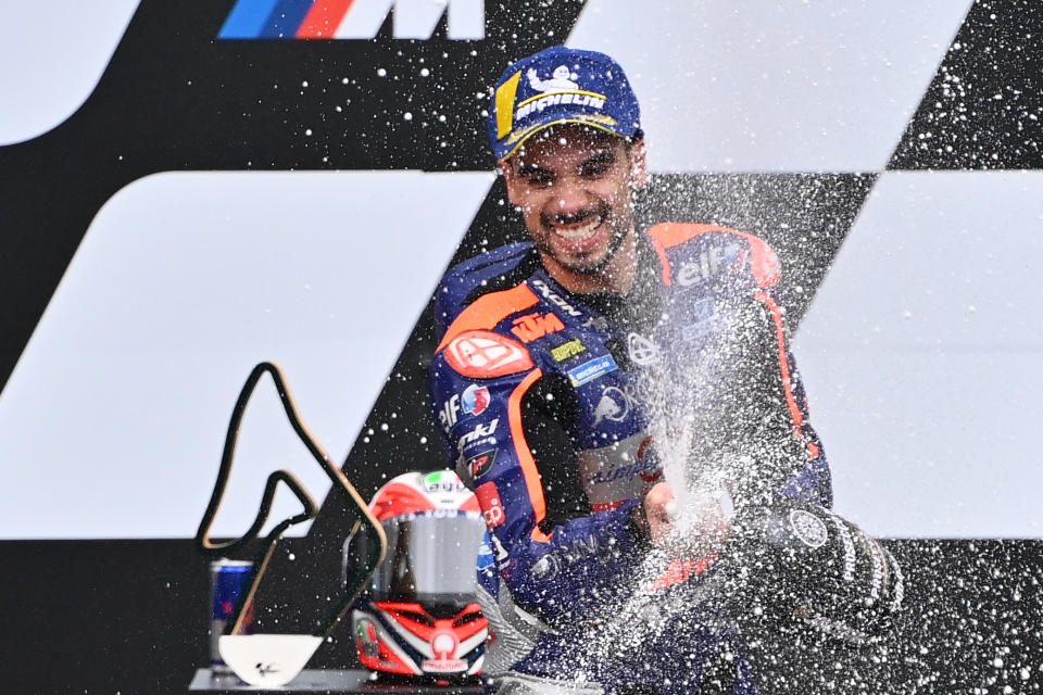 Portuguese rider Miguel Oliveira smiles and sprays champagne after winning.