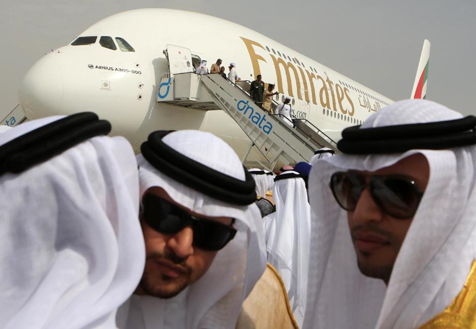 Emirati officials greet each other in front of an Emirates Airbus A380 on display during the opening day of the Dubai Airshow in Dubai, United Arab Emirates, Sunday Nov. 17, 2013. The Dubai Airshow is seen as an increasingly important barometer on the state of the industry and the rising roles of the big-spending Gulf carriers Etihad, Qatar Airways and Emirates as they compete for routes and critical stopover traffic between Asia and Europe and the Americas. (AP Photo/Kamran Jebreili)