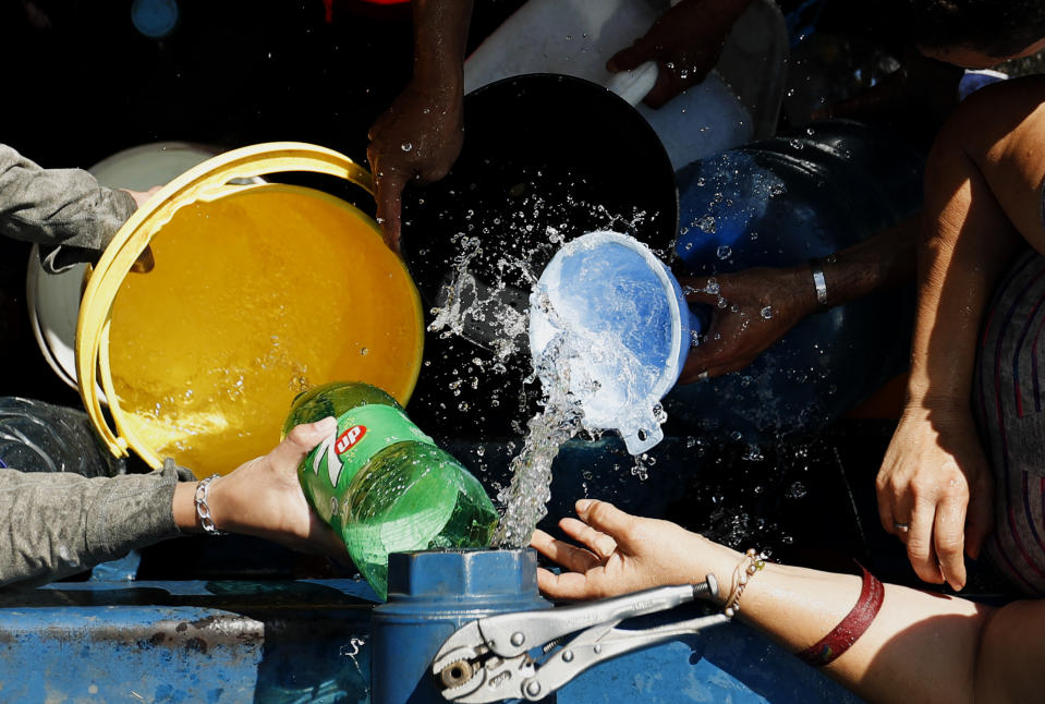 People collect water from a truck that delivers water during rolling blackouts, in Caracas, Venezuela, Tuesday, March 12, 2019. The blackout marked another harsh blow to a country paralyzed by turmoil as the power struggle between Venezuelan President Nicolas Maduro and opposition leader Juan Guaido stretches into its second month and economic hardship grows. (AP Photo/Eduardo Verdugo)