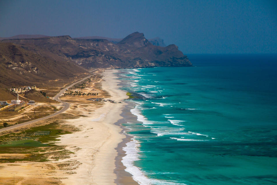 The coastal fringe, watched over by the Dhofar Mountains, is made up of long, white-sand beaches dotted with palm trees - Credit: GETTY