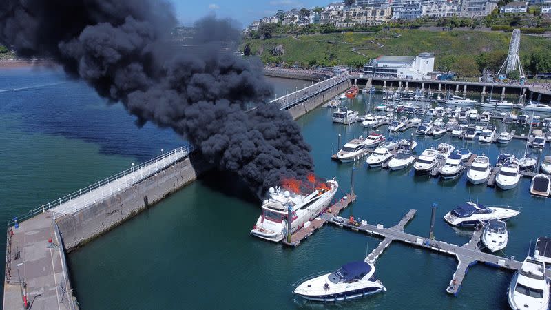 Thick black smoke rises from a fire on a yacht, at Torquay harbour