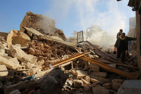 Smoke rises while men inspect damaged buildings after an airstrike on the rebel-held town of Darat Izza, province of Aleppo, Syria November 5, 2016. REUTERS/Ammar Abdullah