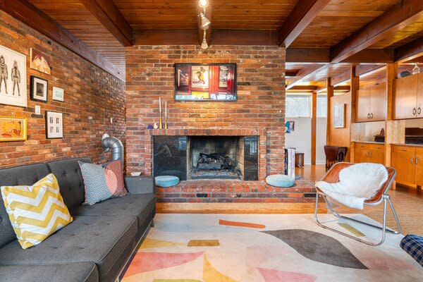 The main living room is anchored by original beamed ceilings and a wide brick fireplace.