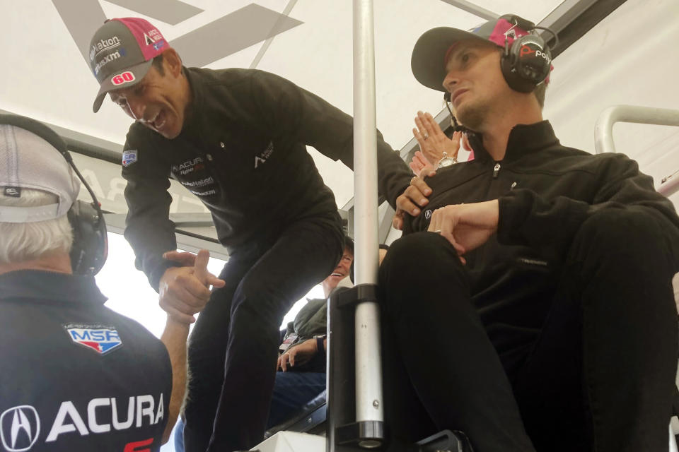 Helio Castroneves, center, congratulates, team owner Mike Shank after teammate Tom Blomqvist won the pole during qualifying, Friday, Sept. 30, 2022, for the IMSA sports cars season-ending Petit Le Mans auto race at Road Atlanta in Braselton, Ga. The team goes into Saturday's race second in the championship standings. The team's third driver, Oliver Jarvis, right, watches. (AP Photo/Jenna Fryer)