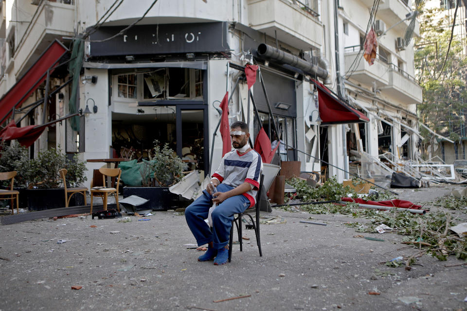 An injured man sits next to a restaurant in the Mar Mikhael neighborhood of Beirut on August 5 in the aftermath of the massive explosion. | Patrick Baz—AFP via Getty Images
