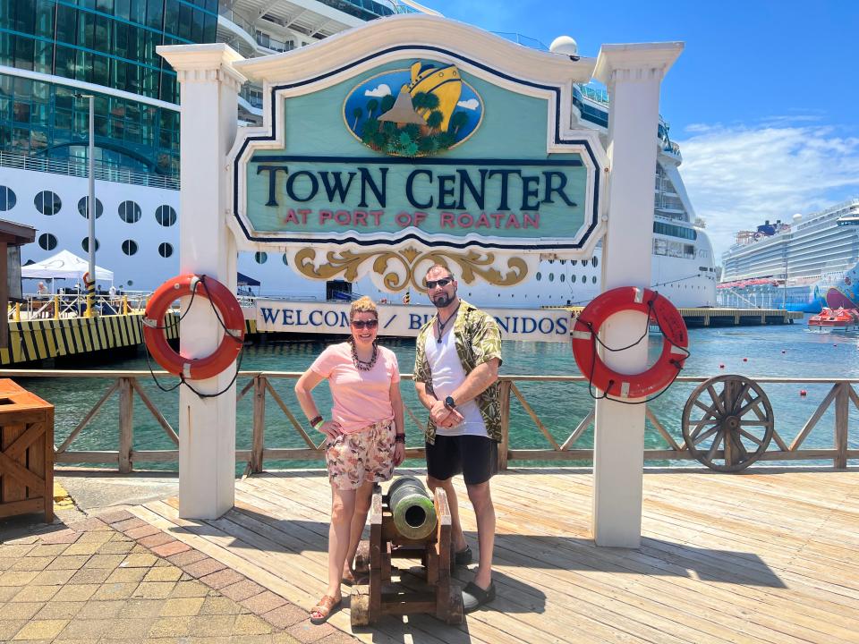 Felicia Slattery and her husband posing in front of port of Roayan town center sign 