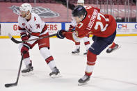 Florida Panthers center Eetu Luostarinen (27) takes a shot against Carolina Hurricanes defenseman Jaccob Slavin (74) during the second period of an NHL hockey game, Monday, March 1, 2021, in Sunrise, Fla. (AP Photo/Wilfredo Lee)