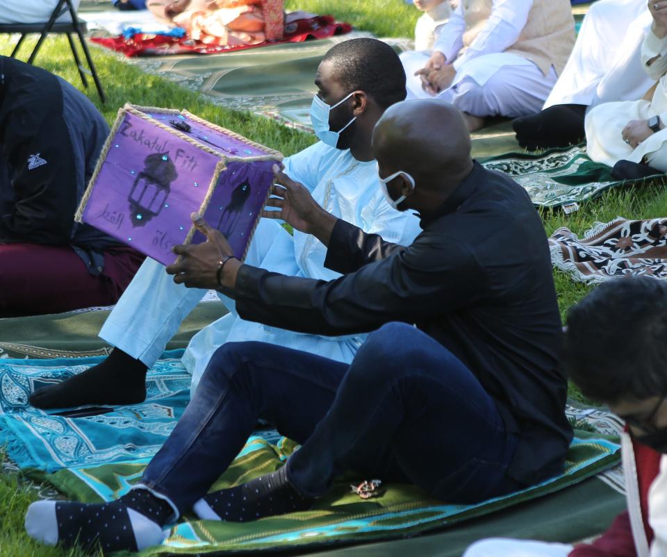 A box is passed around on the last day of Ramadan to collect donations for the needy in 2021.