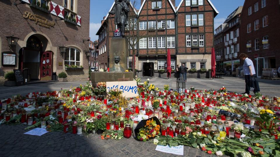 Trauerkerzen und Blumen liegen vor dem Unglücksort in Münster. Foto: Friso Gentsch