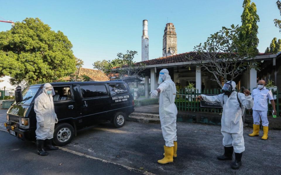  A municipal worker has his body sprayed with disinfectant after he carried a coffin of coronavirus related victim to the crematorium at the public cemetery in Colombo, Sri Lanka - CHAMILA KARUNARATHNE/EPA-EFE/Shutterstock 