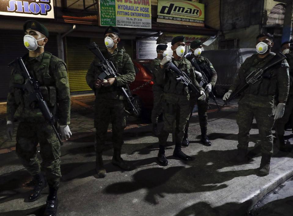 Filipino army troopers wearing protective masks arrive to augment police in Valenzuela, metropolitan Manila, Philippines early Sunday March 15, 2020. Thousands of Philippine police, backed by the army and coast guard, have started sealing the densely populated capital from most domestic travelers in one of Southeast Asia's most drastic containment moves against the coronavirus. For most people, the new coronavirus causes only mild or moderate symptoms. For some, it can cause more severe illness, especially in older adults and people with existing health problems. (AP Photo/Aaron Favila)