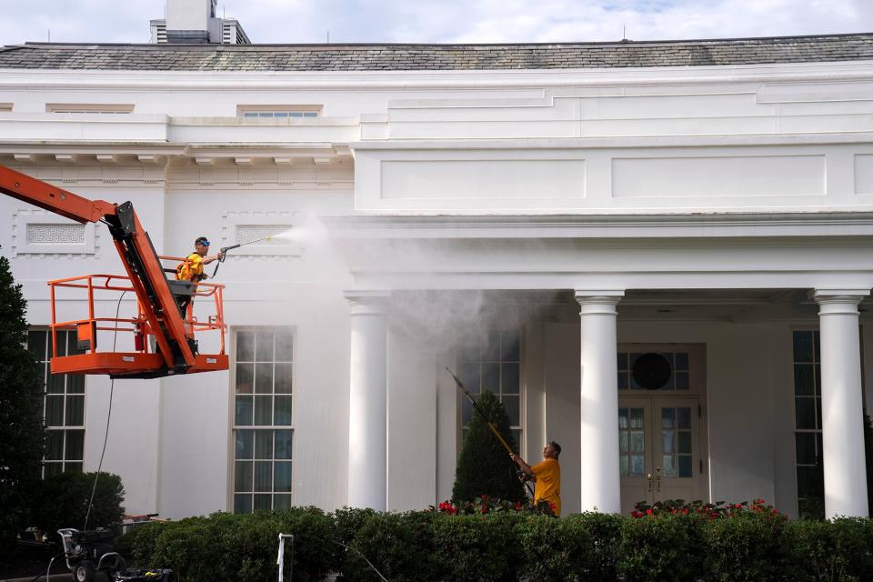 Maintenance workers power wash the exterior of the White House