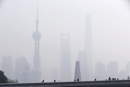 People walks on a bridge in front of the financial district of Pudong amid heavy smog in Shanghai, China, December 15, 2015. REUTERS/Aly Song