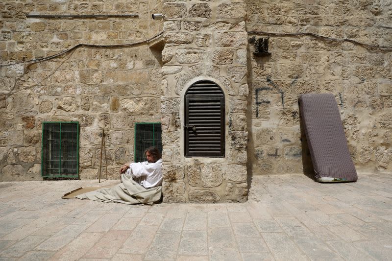 A man rests next to a bronze sculpture by Italian artist Alessandro Mutto at one of the Stations of the Cross along the Via Dolorosa, amid the coronavirus disease (COVID-19) outbreak in Jerusalem's Old City