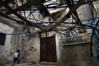 A Palestinian student walks under improvised water pipes and power cables in an alley in the Bourj al-Barajneh Palestinian refugee camp, in Beirut, Lebanon, Tuesday, Jan. 18, 2022. The agency for Palestinian refugees, or UNRWA, appealed Wednesday to the international community to donate tens of millions of dollars to help improve living conditions for Palestinians in crisis-hit Lebanon. UNWRA is asking for an additional $87.5 million to provide Palestinian refugees with cash assistance to the poorest, cover hospital expenses, as well as transportation for children so that they can go to school. (AP Photo/Hussein Malla)