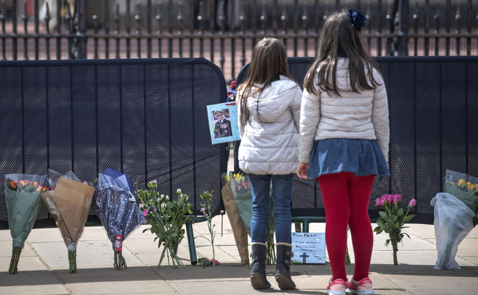 <p>Two girls look at flowers and messages left by members of the public outside Buckingham Palace, London, following the death of the Duke of Edinburgh at the age of 99 on Friday. Picture date: Tuesday April 13, 2021.</p>
