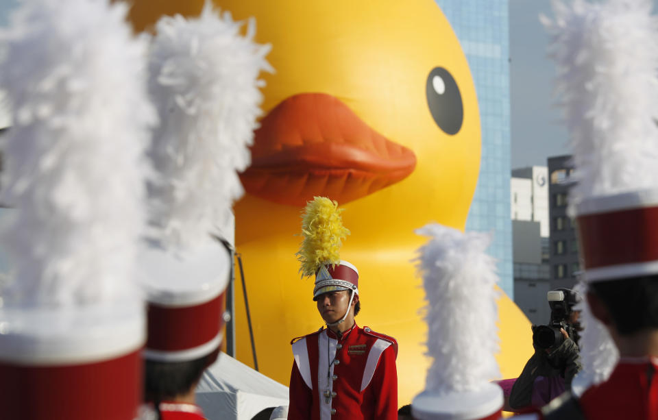 A school marching band leader waits in the heat to perform for the arrival of a giant yellow duck in the port of Kaohsiung, Taiwan, Thursday, Sept. 19, 2013. Despite the heat, thousands flocked to the port of Kaohsiung, the first leg of the Taiwan tour, to see Dutch artist Florentijn Hofman's famous 18 meter (59 foot) yellow duck, a gigantic version of the iconic bathtub toy used by children around the world. (AP Photo/Wally Santana)