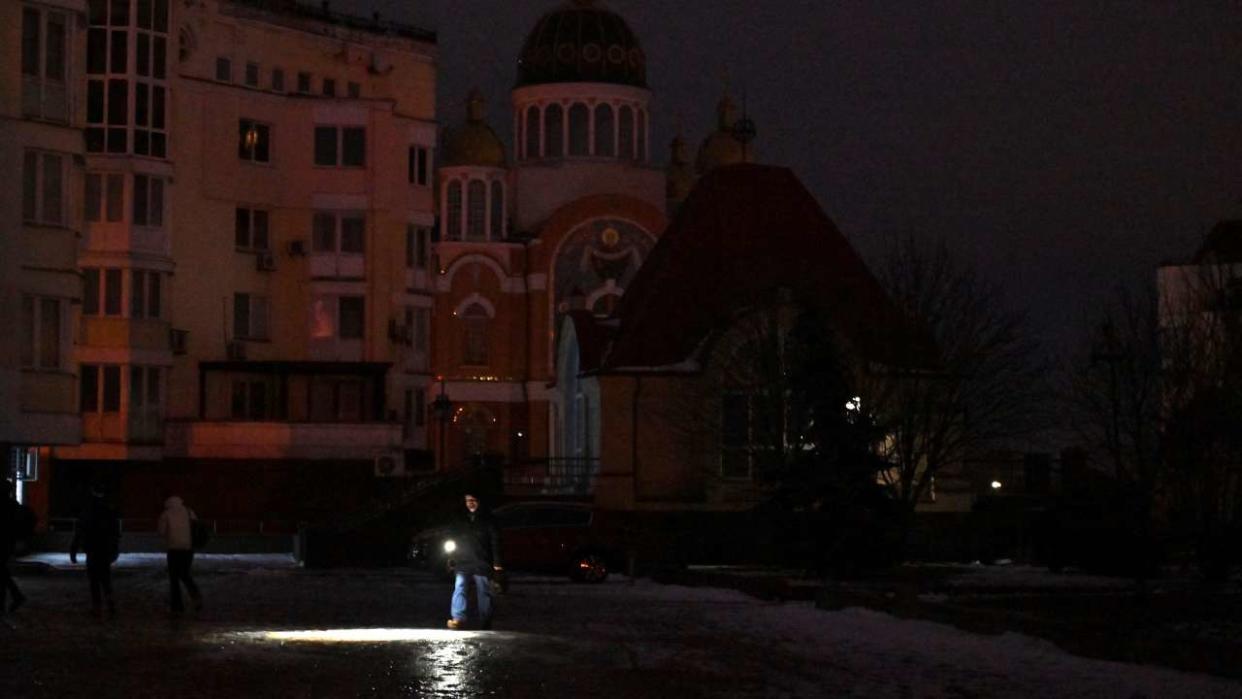 Passers-by light their way with flashlights during a blackout in the Ukrainian capital of Kyiv, on December 20, 2022, amid the Russian invasion of Ukraine. (Photo by Sergei SUPINSKY / AFP)