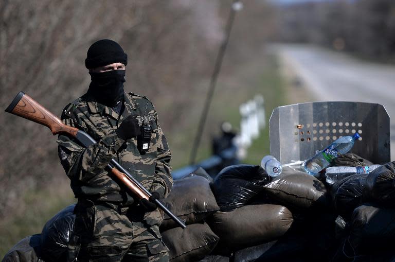 A masked armed man stands guard at a check point on the road from Simferopol to Sevastopol on March 13, 2014