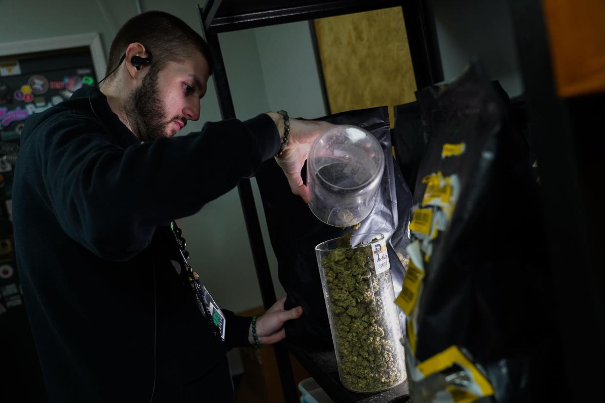 Pure Lapeer assistant manager Tanner Karns refills a jar of Kush Mints cannabis flowers before filling an order at Pure Lapeer in Lapeer on Wednesday, November 24, 2021.