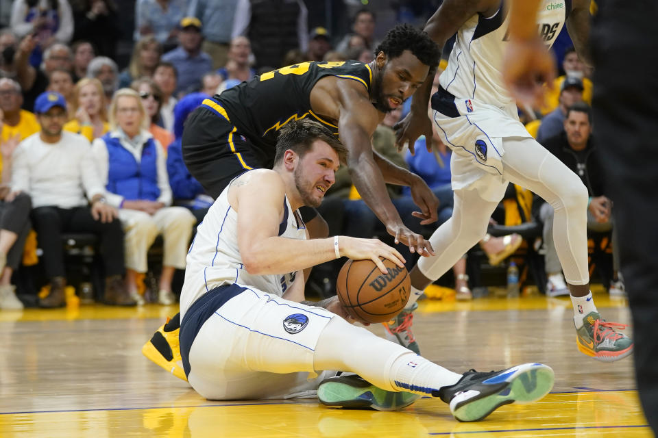Dallas Mavericks guard Luka Doncic, bottom, holds onto the ball under Golden State Warriors forward Andrew Wiggins during the second half of Game 5 of the NBA basketball playoffs Western Conference finals in San Francisco, Thursday, May 26, 2022. (AP Photo/Jeff Chiu)