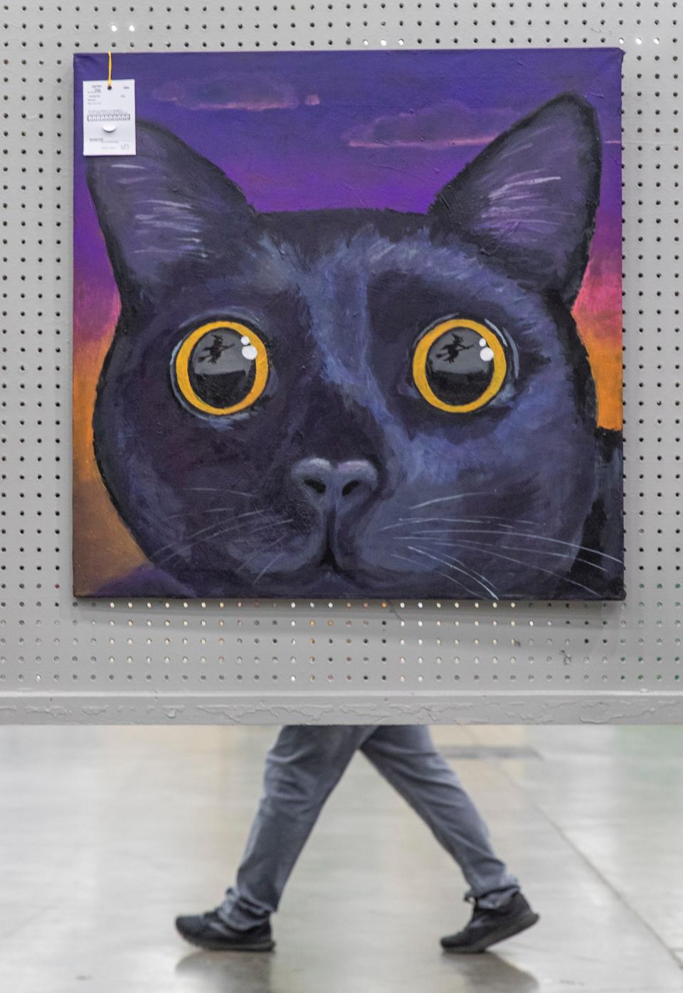 A man walked behind a painting of a cat on the opening day at the Kentucky State Fair. Aug. 19, 2021