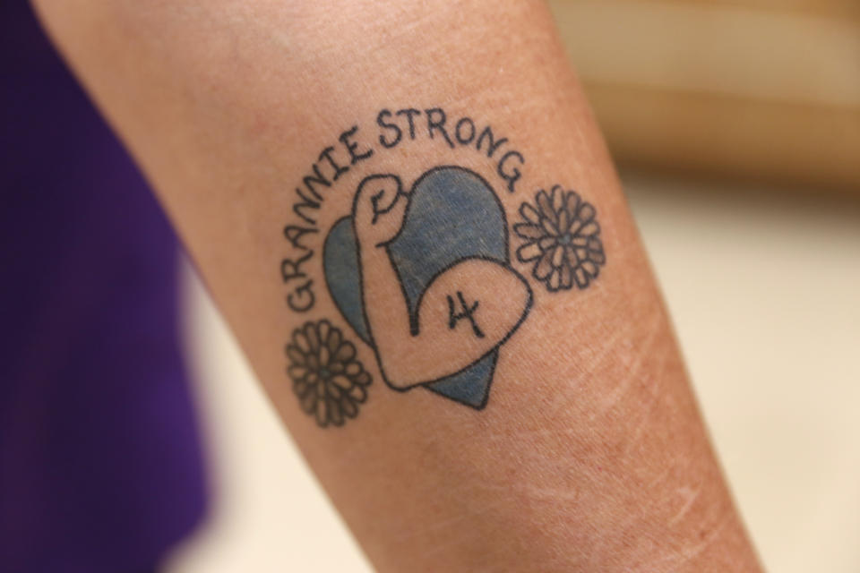 Jan Kwiatkowski shows her “Granny Strong” tattoo after a Milwaukee Dancing Grannies practice in Milwaukee on Wednesday, Nov. 2, 2022. Kwiatkowski has been a Dancing Granny since 2018 and is now one of the group’s leaders. The number “4” in the tattoo represents three group members and another member’s husband who were among those killed when the driver of an SUV struck them at a Christmas parade last November in Waukesha, Wisconsin. At events and after practices, Kwiatkowski, a family therapist and ordained chaplain, often encourages group members to form a circle and place their pompoms together as they shout “Granny Strong!” in unison. It has become their rallying cry since tragedy struck. (AP Photo/Martha Irvine)