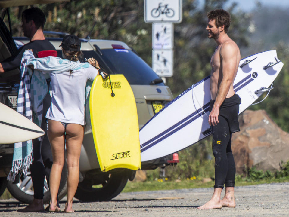 Liam Hemsworth holds on to his surfboard in Byron Bay