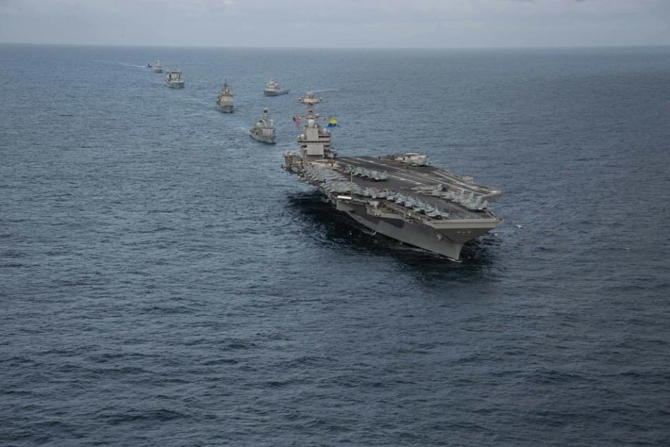 a line of military ships sail in formation