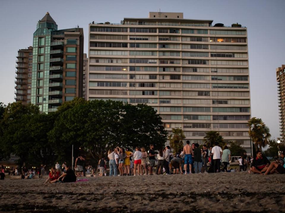 People gather at English Bay Beach in Vancouver during last summer's heat wave. Changing building codes to require cooling in existing dwellings could take decades, experts warn. But there are things people can do now to deal with extreme heat. (Darryl Dyck/The Canadian Press - image credit)