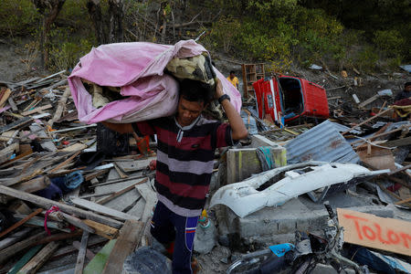 A man carries his belongings from his house after tsunami hit Lolik beach near Palu, Sulawesi island, Indonesia October 1, 2018. REUTERS/Beawiharta