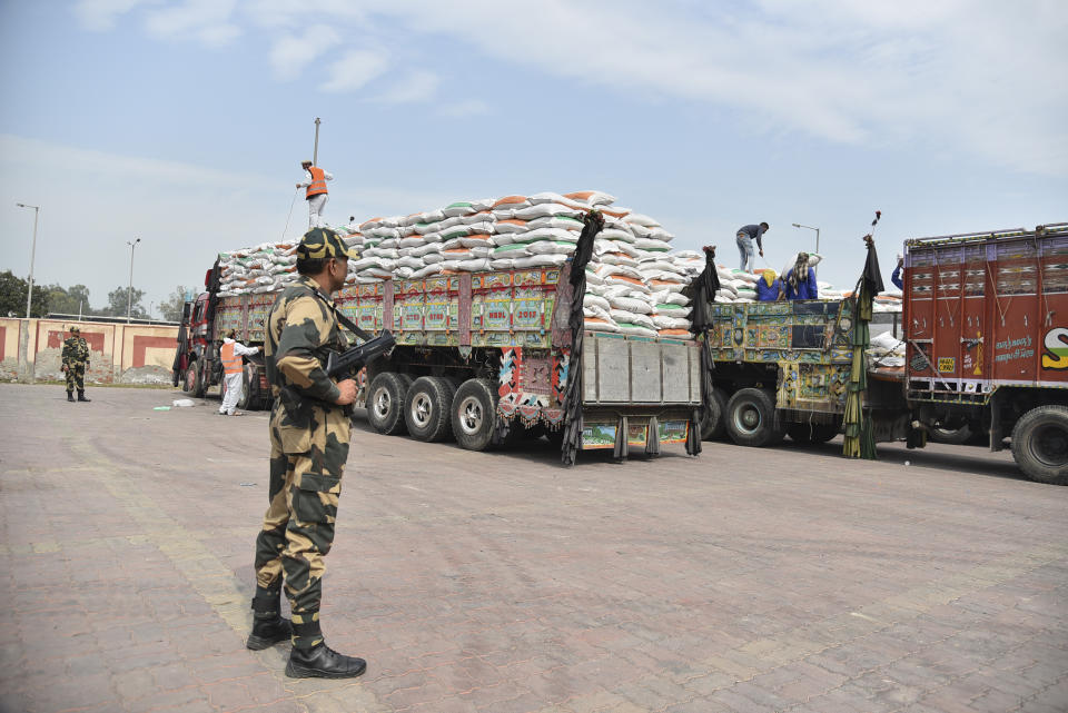 An Indian Border Security Force soldier guards as trucks carrying wheat from India wait to pass through the Attari-Wagah border between India and Pakistan, near Amritsar, India, Tuesday, Feb.22, 2022. Last week, Pakistan officials said the country would allow nuclear rival India to deliver wheat to Afghanistan, where millions are struggling through acute food shortages. The arrangement comes more than three months after India announced it would deliver 50,000 metric tons of wheat and life-saving medicine to Afghanistan. (AP Photo/Prabhjot Gill)