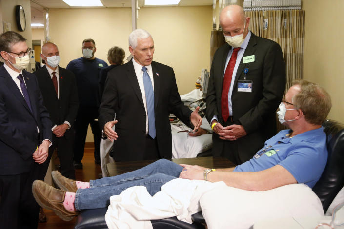 Vice President Mike Pence, center, visits Dennis Nelson, a patient who survived the coronavirus and was going to give blood, during a tour of the Mayo Clinic Tuesday, April 28, 2020, in Rochester, Minn., as he toured the facilities supporting COVID-19 research and treatment. Pence chose not to wear a face mask while touring the Mayo Clinic in Minnesota. It's an apparent violation of the world-renowned medical center's policy requiring them. (AP Photo/Jim Mone)