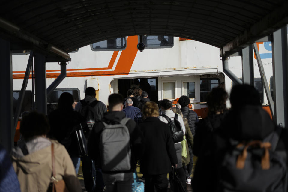 Passengers board a Lisbon bound ferry boat in Almada, across the Tagus river from Lisbon, Tuesday, March 14, 2023. In Portugal, the housing problem has been magnified by tourism, whose robust growth before the pandemic has come roaring back, as well as an influx of foreign investors who found relatively low real estate prices in Lisbon and have been driving up prices that force local people out of their neighborhoods and often out of town. (AP Photo/Armando Franca)