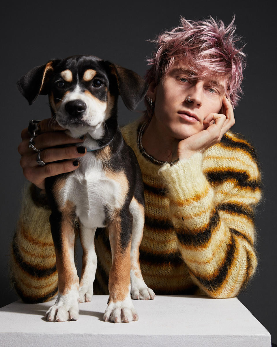 MGK posing with the same puppy, this time giving a smoldering look while the puppy stands next to him