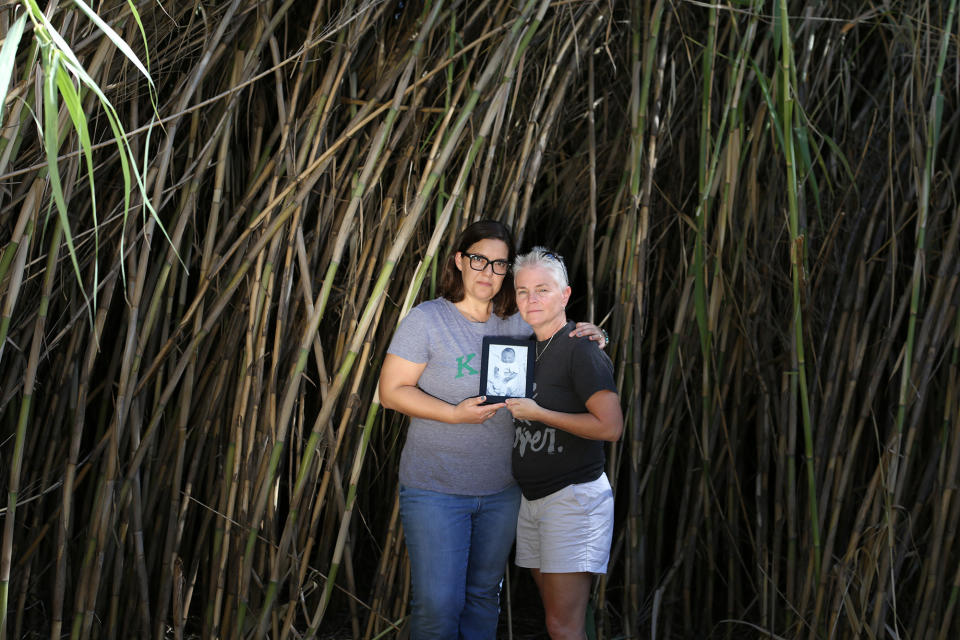 Sarah Toig and Rae-Ann Wood at the bamboo-thick edge of the care farm’s property in Sedona, Ariz. The couple holds a photo of their son, Noah, who was stillborn. (Photo: Caitlin O’Hara for Yahoo Lifestyle)