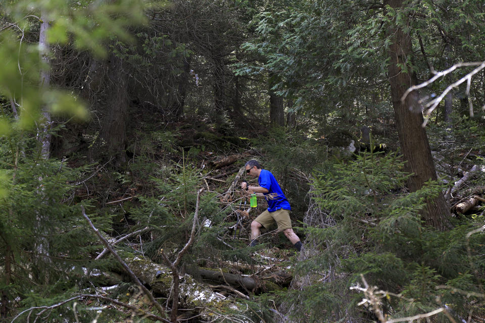 Dustin Ricci, of Storrs, Conn., hikes up the trail to Indian Head summit inside the Adirondack Mountain Reserve, Saturday, May 15, 2021, near St. Huberts, N.Y. A free reservation system went online recently to control the growing number of visitors packing the parking lot and tramping on the trails through the private land of the Adirondack Mountain Reserve. The increasingly common requirements, in effect from Maui to Maine, offer a trade-off to visitors, sacrificing spontaneity and ease of access for benefits like guaranteed parking spots and more elbow room in the woods. (AP Photo/Julie Jacobson)