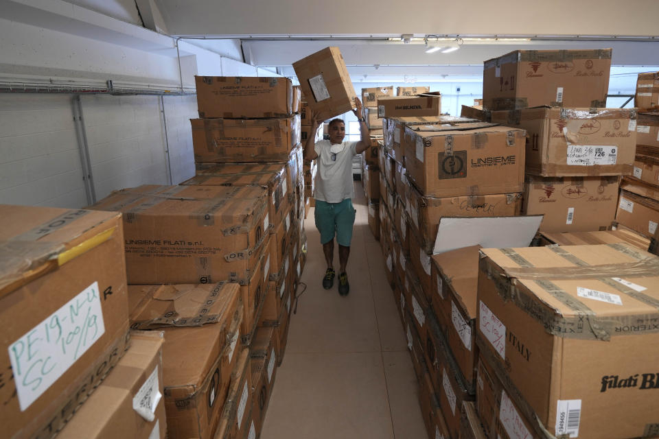 Cose di Maglia factory's storekeeper Malik goes through boxes of unsold D.Exterior clothes intended for Moscow's stores, in Brescia, Italy, Tuesday, June 14, 2022. Small Italian fashion producers are still allowed to export to Russia, despite sanctions, as long as the wholesale price is under 300 euros. But they are having a hard time getting paid, due to restrictions tied to the financial sector. (AP Photo/Luca Bruno)