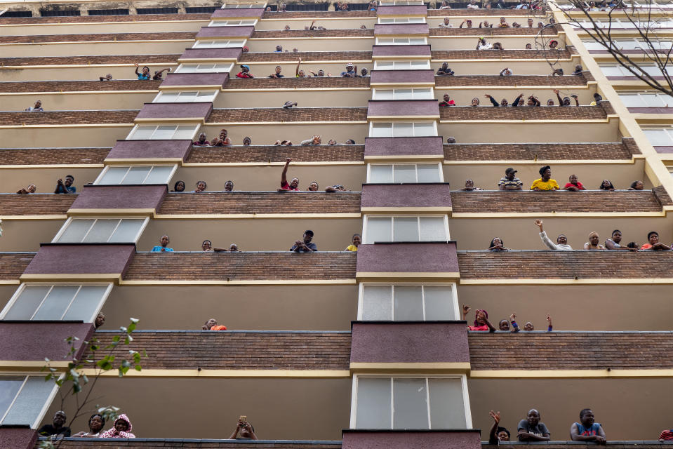 Residentes de un edificio de Hillbrow, un barrio densamente poblado de Johannesburgo, pasando el tiempo en sus balcones, sin tapabocas, el 27 de marzo del 2020, en plena pandemia del coronavirus. (AP Photo/Jerome Delay)
