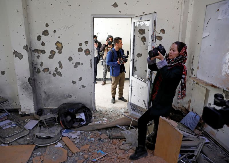 Afghan journalists film inside a classroom after yesterday's attack at the university of Kabul