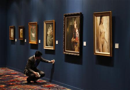 A member of staff cleans a wall prior to the opening of an auction preview of 'modern and contemporary Chinese art' during Sotheby's Beijing Art Week in Beijing, November 28, 2013. REUTERS/Kim Kyung-Hoon